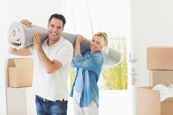 Couple carrying a rolled up rug, and for some reason, they are very delighted about it.